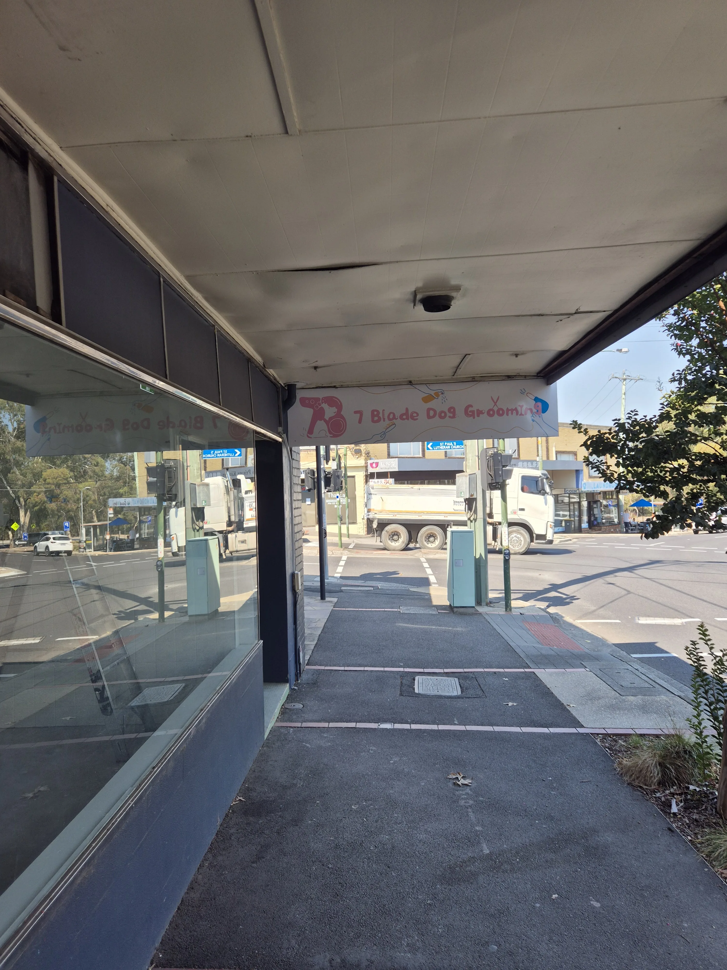7 Blade Dog Grooming shopfront on Elgar Rd, Box Hill South — pink banner sign under the footpath awning